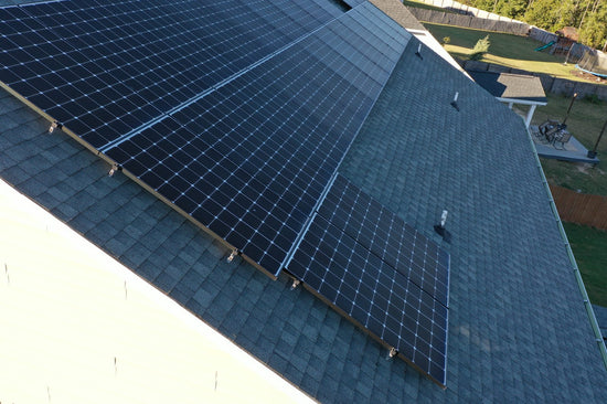 Close aerial view of a clean solar panel array laid flush on architectural shingles.